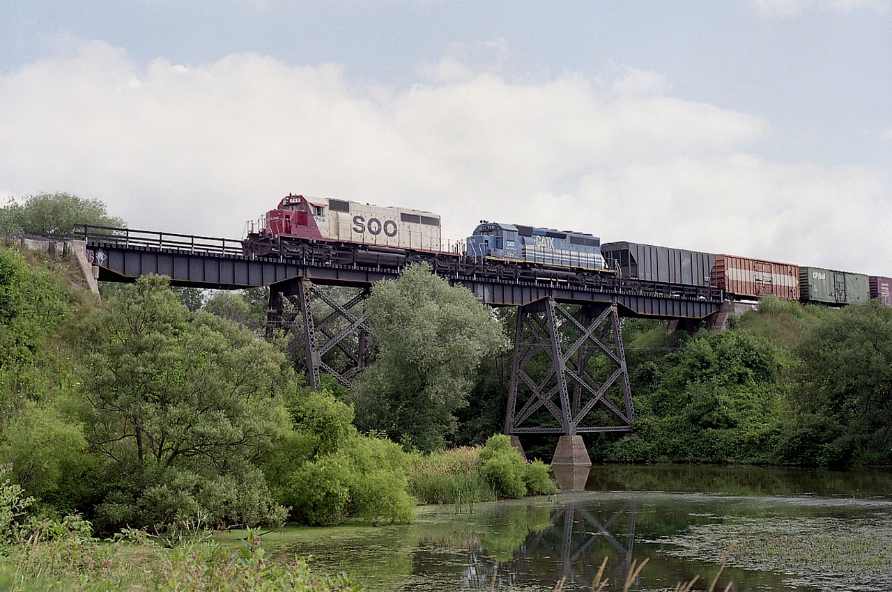 To me, this is a nice change from the CP red. SOO 768 and GATX 7371 hustle westbound over the Middle Thames River bridge.
This was a nice place to shoot so long as you could get to the waters' edge. Lot of bullrushes, swamp and muck as well as foliage to contend with. The SOO SD40-2 along with its' sisters were gone from the CP by 2012.