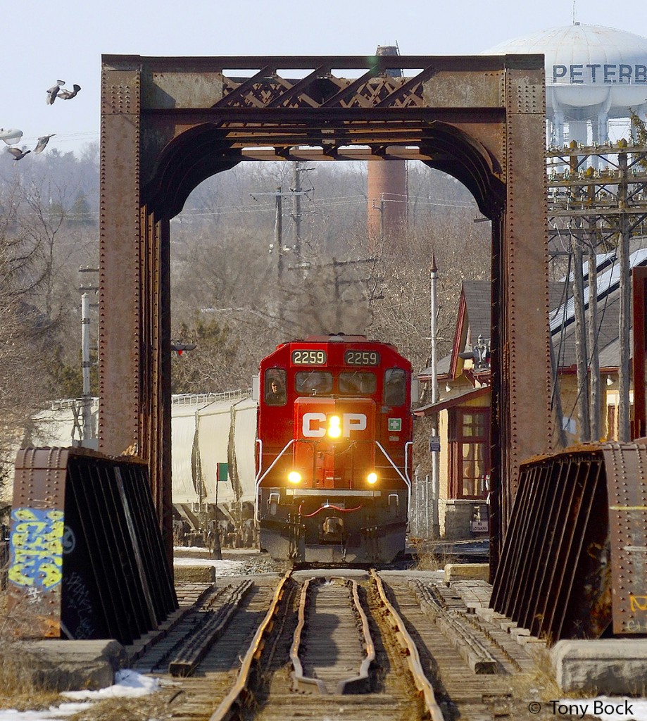 On its way to Havelock and Blue Mountain to serve the nepheline syenite mine, CP train T08 passes Peterborough station (built 1884) and crosses the Otonabee River bridge (built 1913) on March 9th, 2021.  The usual power is three locomotives, today led by GP20C-ECO 2259.