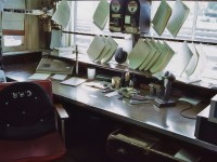 <br>
<br>
   The ubiquitous Telegrapher's Bay
<br>
<br>
   a k a Operator's desk 
<br>
<br>
    at CP Rail  G U , Guelph Junction, June 8, 1986 Kodachrome by S.Danko
<br>
<br>
   Noteworthy equipment  & features 
<br>
<br>
   for the benefit of those who maybe unfamiliar with The Eighties (& prior)
<br>
<br>
    and to remind some of us as to what was !,
<br>
<br>
    from right to left: 
<br>
<br>
   extreme right is radio equipment receivers / transmitter boxes, radio microphone, 
<br>
<br>
   analogue paper punch, analogue paper stapler, cigarette / cigar ashtray, small bottle paper white out, 
<br>
<br>
   at centre top east - west track occupancy circuit indicator boxes, immediately below is an analogue radio speaker, 
<br>
<br>
    hanging in front of the windows are completed train orders / train operational instructions forms – to be assembled as appropriate depending on the train direction and bound together by elastic / string prior to attachment to the train order hoop(s),
<br>
<br>
    left side of desk is an analogue intercom /  wire line bell telephone with microphone, 
<br>
<br>
    at top left is the east – west station signal indicator levers, 
<br>
<br>
    at centre extreme left is an analogue combined keyboard & printer device – paper is inserted at the top of the device and rolled manually into the device by means of manually operated roller with handle turn knobs at each extreme end , the Operator would then manual press the appropriate QWERTY keys to record on the paper the required instructional information, 
<br>
<br>
    and at top left is an analogue pencil sharpener, insert the pencil and turn the crank at an appropriate RPM. 
<br>
<br>
   did I miss anything?   
<br>
<br>
   What's interesting: The NASA STS-1 a k a  the Space Shuttle, first flight: April 12, 1981.
 <br>
<br>
   Cheers !
<br>
<br>
   sdfourty
