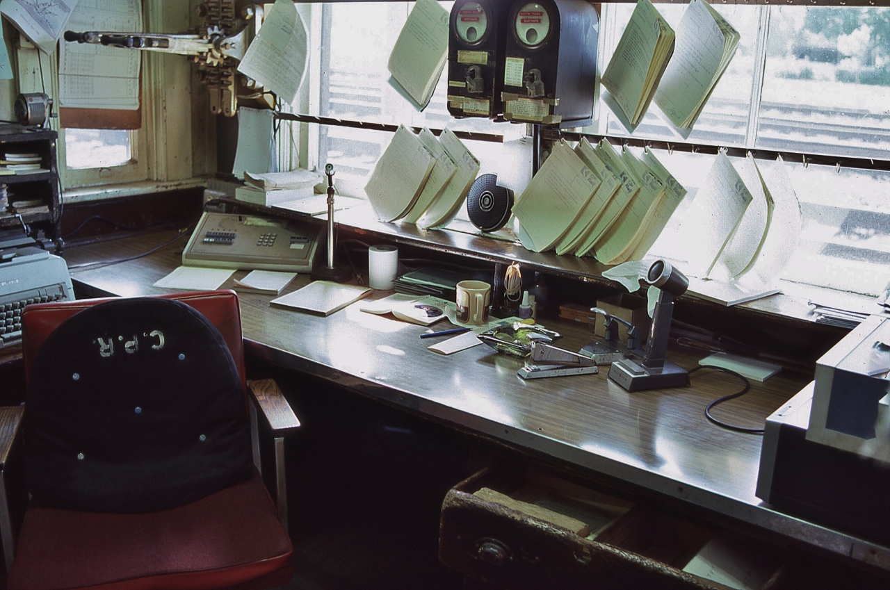 The ubiquitous Telegrapher's Bay


   a k a Operator's desk 


    at CP Rail  G U , Guelph Junction, June 8, 1986 Kodachrome by S.Danko


   Noteworthy equipment  & features 


   for the benefit of those who maybe unfamiliar with The Eighties (& prior)


    and to remind some of us as to what was !,


    from right to left: 


   extreme right is radio equipment receivers / transmitter boxes, radio microphone, 


   analogue paper punch, analogue paper stapler, cigarette / cigar ashtray, small bottle paper white out, 


   at centre top east - west track occupancy circuit indicator boxes, immediately below is an analogue radio speaker, 


    hanging in front of the windows are completed train orders / train operational instructions forms – to be assembled as appropriate depending on the train direction and bound together by elastic / string prior to attachment to the train order hoop(s),


    left side of desk is an analogue intercom /  wire line bell telephone with microphone, 


    at top left is the east – west station signal indicator levers, 


    at centre extreme left is an analogue combined keyboard & printer device – paper is inserted at the top of the device and rolled manually into the device by means of manually operated roller with handle turn knobs at each extreme end , the Operator would then manual press the appropriate QWERTY keys to record on the paper the required instructional information, 


    and at top left is an analogue pencil sharpener, insert the pencil and turn the crank at an appropriate RPM. 


   did I miss anything?   


   What's interesting: The NASA STS-1 a k a  the Space Shuttle, first flight: April 12, 1981.
 

   Cheers !


   sdfourty