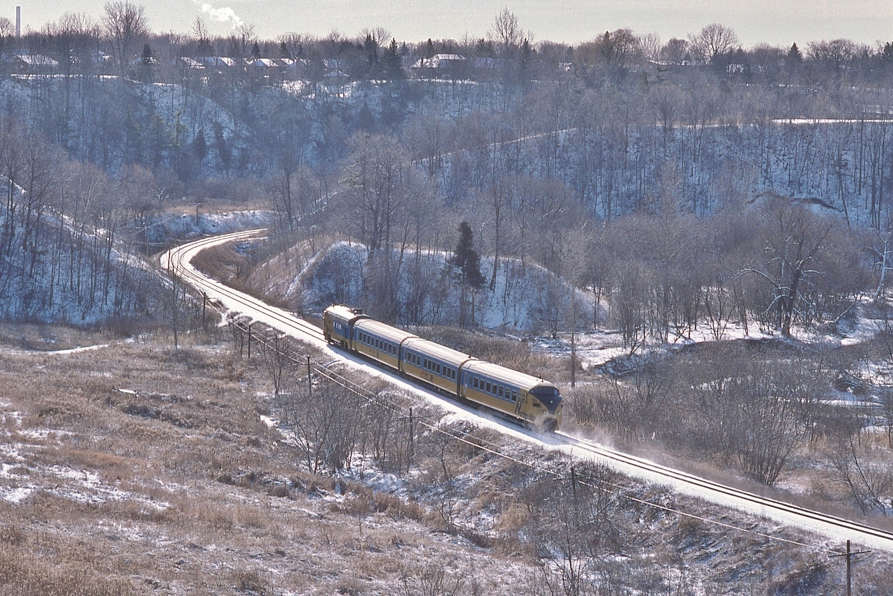 Saturday only VIA train #120 is on time for a 13:10 arrival at the Union Depot


   The view from Bartley Dr, East York,, January 3, 1987 Kodachrome by S.Danko


   Notable: The Northlander – it is NOT !


   the VIA time table states “ Nos. #121-122  O.N. trains operated on CN lines between Toronto on North Bay”


   [no specific operating comment in the timetable regarding the operation of trains 120 (Sat), 123 ( Fri., Sun), 124 (Sun); presumably these operated by VIA using ONR equipment]


   The Location: near Bala Sub mile 7, passenger train speed limit through the sharp curves: 35 m.p.h.; at lower left is a former East York works land (garbage dump) fill site (accessed from Northline Drive), East York Parkview Hills bungalows at upper left, the Flemingdon Park golf course is just out of view at extreme at right, at extreme upper left is the single tall (1971 built) exhaust stack for the Richard L. Hearn Generating Station (operating 1951 to 1983) at 44 Unwin Avenue located on the Toronto Port Lands 


   sdfourty