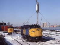  A pair of VIA FPA-4's (6777 & 6789) sun themselves at the CN Windsor roundhouse alongside the Detroit River on March 3rd 1984 as a pair of CN switchers, one coupled to a reacher car to switch the N&W car ferries, work the yard. Across the river both Bob-Lo boats, Columbia and St Clair are tied up for the season adjacent to Joe Louis Arena. The top of Detroit's Michigan Central Station can also bee seen hiding behind "The Joe". 