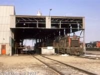 A group of CN SW1200RS units lead by 1324 (sporting white extra flags) sit under the canopy in the open servicing bays at the east end of Toronto Yard's diesel shop, awaiting attention from shop forces. Other units on the shop tracks include other SW1200RS, GP9, and GP38-2 models - typical roadswitcher and local power at the time.  A 1200-series unit still in the old green and gold paint is visible under the canopy behind 1324, one of many units that evaded the new "noodle" logo and paint into the early 70's.<br><br>CN's Toronto Yard (later MacMillan Yard) diesel shop was originally built near the north-west end of the yard in the mid-1960's, and was expanded over time. The canopy area here was extended and enclosed sometime in the 1980's.<br><br><i>Original photographer unknown, Dan Dell'Unto collection slide.</i>
