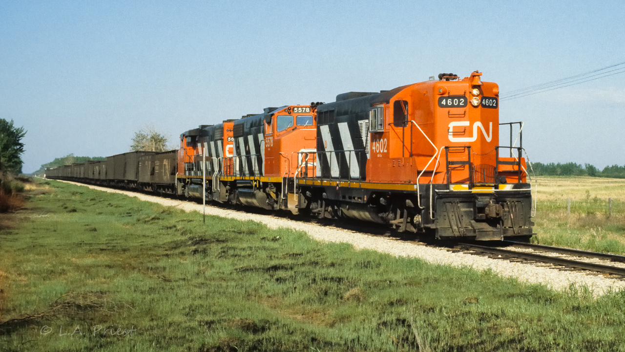On a lovely Sunday May morning, birds chirping, sounds of summer in the air, comes along something else, not quite the same melody as the others, but, it sure photographs well with the surroundings. A unit train of 33 empties is on the way north at 9:00. You always went home feeling so satisfied, even without taking a photo, after a moment like this [even better when the kids came :^)]. Taken with Ektachrome 200 at mile 26.6.
