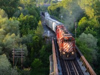 The sun’s setting quick but still has just enough left to shine CP T69 westbound over the Thames River in Woodstock as they pull their train out of Coakley Siding after meeting an eastbound. CP 3018 west in its endangered action red stripes was a great way to end off this warm summer day, photos like this make me look forward to summer months, although this scene is now fading onto the unlikely side.