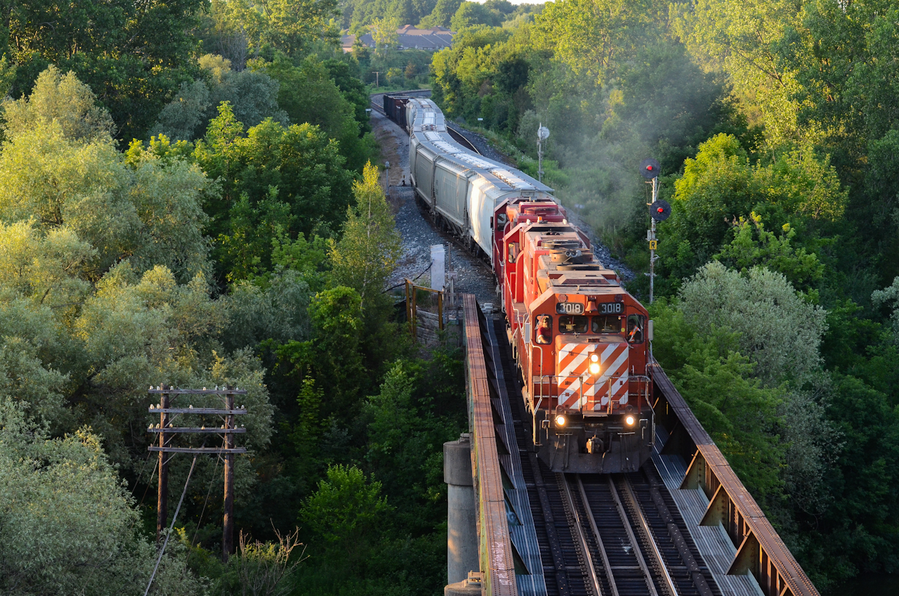 The sun’s setting quick but still has just enough left to shine CP T69 westbound over the Thames River in Woodstock as they pull their train out of Coakley Siding after meeting an eastbound. CP 3018 west in its endangered action red stripes was a great way to end off this warm summer day, photos like this make me look forward to summer months, although this scene is now fading onto the unlikely side.