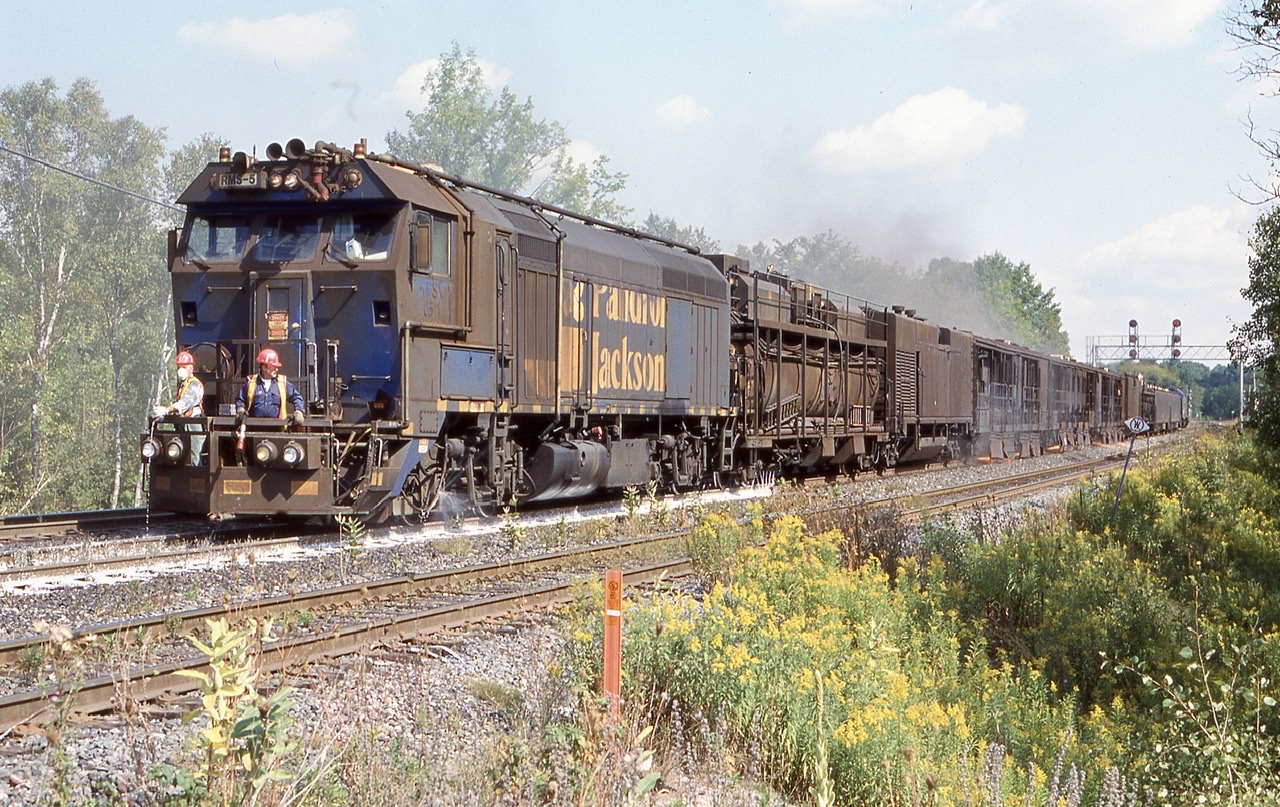 Rail grinding has always been an interesting part of railroading, no matter what time of day it is. Typically most grinding seems to happen at night but certainly not always. P&J, latter HTT had some interesting train sets roaming the rails prior to the more common sets we see today. RMS set #5  was powered by F40PH-2C RMS- 511, one of only 4 of these units built. It unfortunately was scrapped years ago. The trailing two passenger cars are ex GO Transit single level cars. Here the train is seen grinding eastbound at Campbellville with sparks flying from under the cars. The men on the end platform are on the constant look out for small fires caused by sparks from the train.
