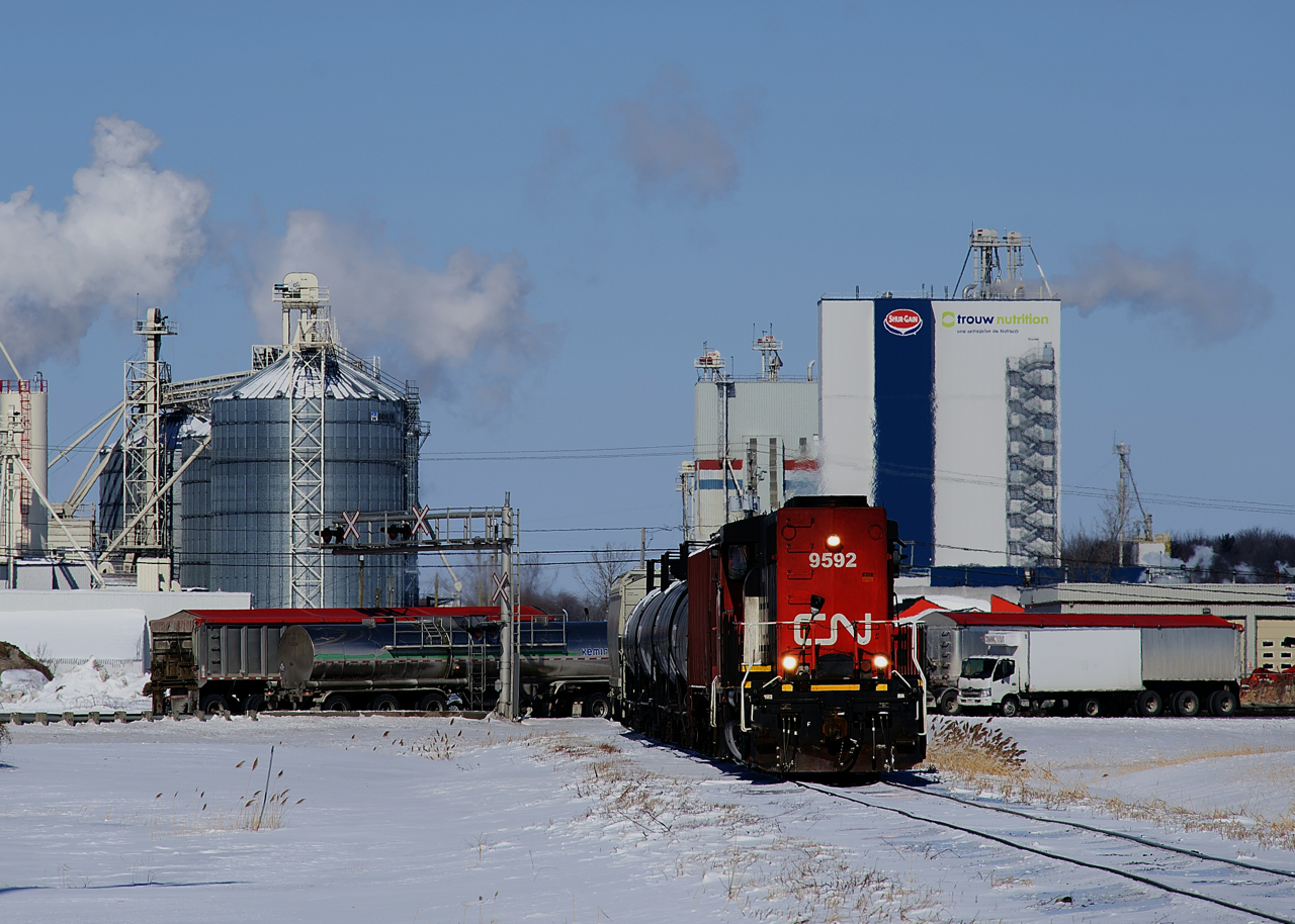CN 519 has just completed another harrowing crossing of the 4-lane, divided Trans-Canada Highway (Autoroute 20 here) as it heads south with CN 9592 and six cars, as road traffic resumes behind it. This will be the second of three trips that the St-Hyacinthe local makes on the St-Jude Spur this day. CN brings cars to Transbordement St-Hyacinthe, which switches cars for a number of clients located north of the highway.