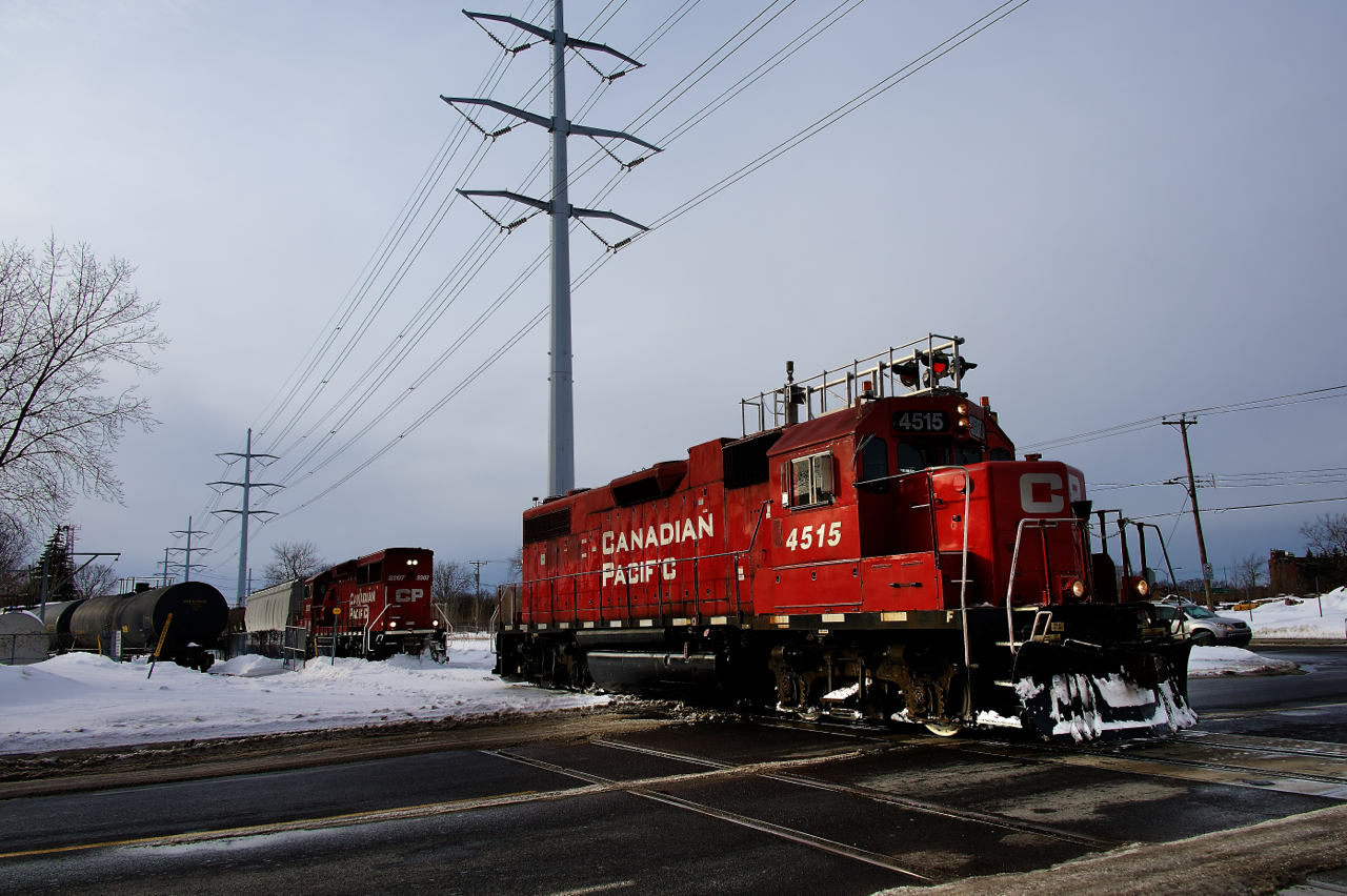 Both CP 4515 and CP 2307 (with cars) are both about to cross Lafleur Avenue at the same time as CP F95 attempts to lift empties from Total Fuel (at left). Iced over flanges would cause them to give up on that.