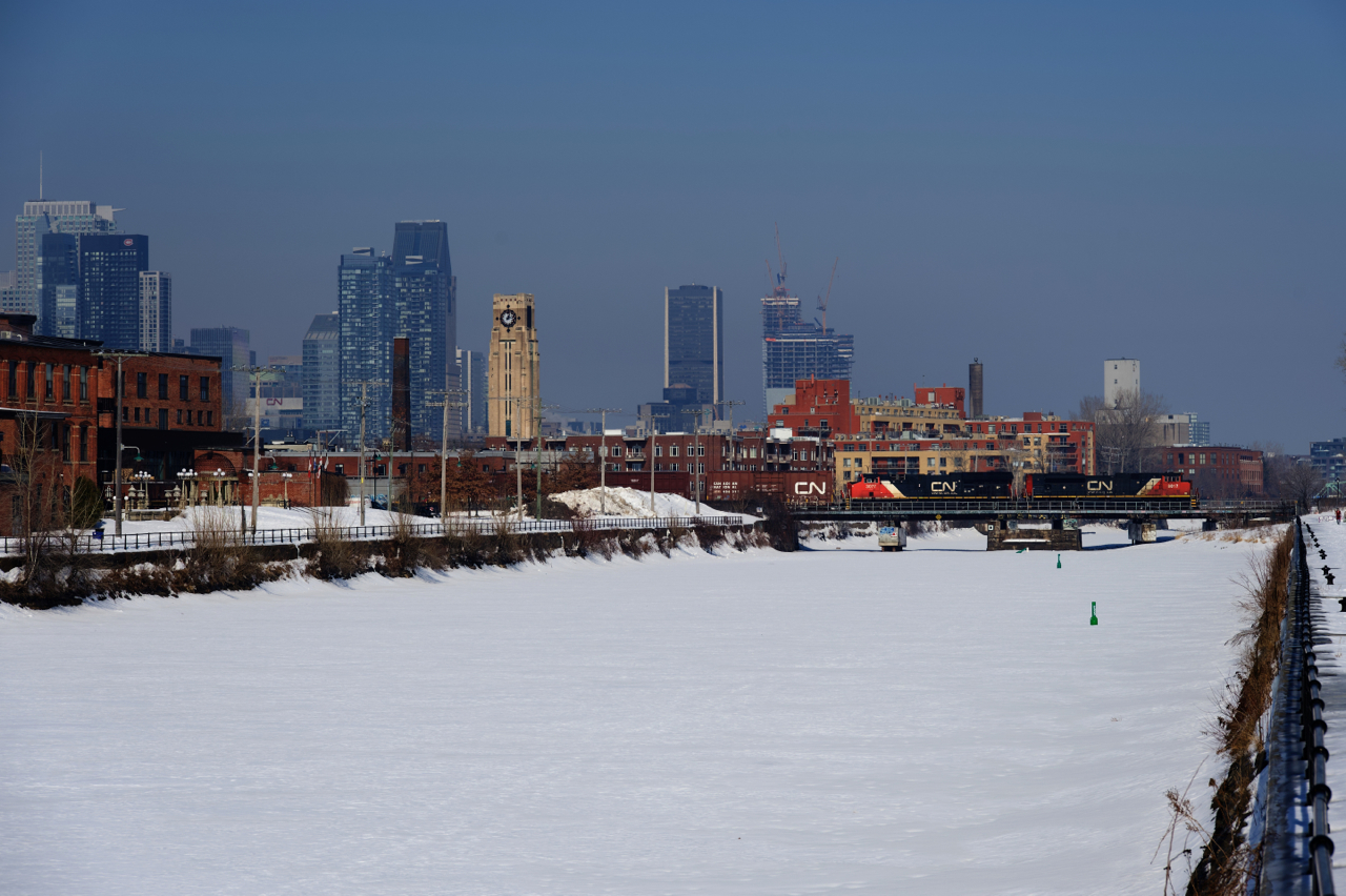 CN 324 is crossing the Lachine Canal with CN 8017 & CN 3077 for power. A CN noodle is visible on the first car and the power, as well as in the far distance at left, on CN's headquarters building.