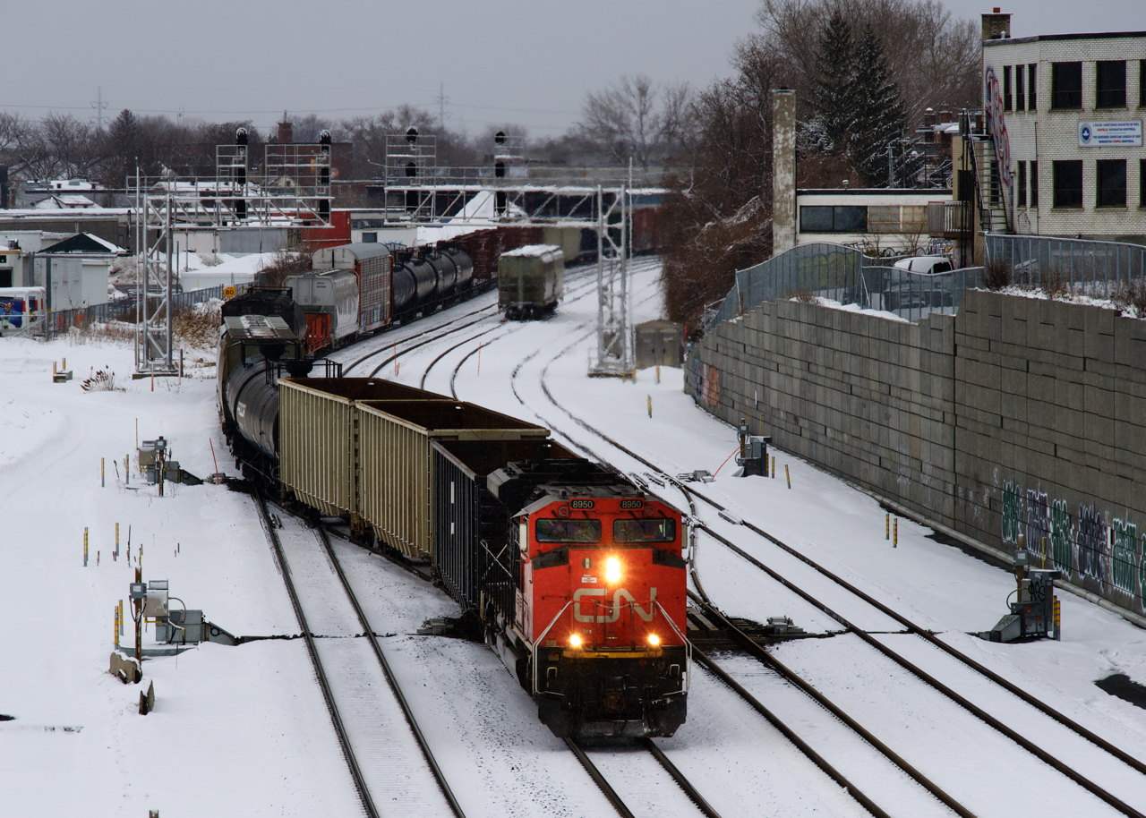 Snow has started to fall as CN X306 crosses over from the north to the south track with CN 8950 and another SD70M-2 mid-train (CN 8825). The train will cross over one more time in a short distance before tieing down on the freight track.