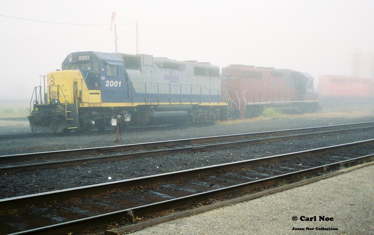During a very foggy morning, RaiLinK 2001 and 2002 share a shop track at North Bay, Ontario. Notes indicate that OVR train 917 was also there with CP 6037 and HATX 751. As well as RaiLink 4203.