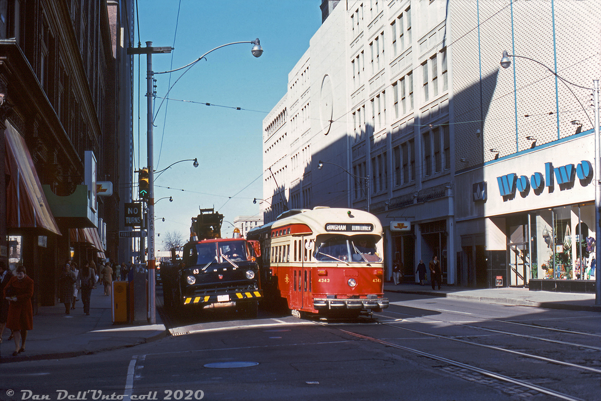In the shadow of retail giants: TTC PCC 4343 is operating on a Downtowner tripper run eastbound to Bingham loop, paused at the lights on Queen Street at Yonge Street. This was long a major downtown Toronto retail corner as on the north side (right) was Eaton's famed Queen Street store, and on the side side was Simpson's (later The Bay's) flagship Toronto location. A Woolworth's was present at the north-west corner, tucked into but separate from Eaton's. The Yonge and Queen streetcar lines ferried Toronto shoppers to/from the downtown department stores here for decades, and eventually the Yonge Subway provided more direct store access and more efficient service. A Ford C-series cabover truck waits at the light alongside (possibly a Bell utility truck).

The Eaton's Queen Street department store, built on land parceled together from various storefronts along Yonge and Queen over the years, was part of Eaton's sprawling downtown holdings which included buildings for mail-order, catalogue, manufacturing, distribution and a secondary Annex/budget store. Despite being spruced up with a coat of white paint, it was all on borrowed time: to the north Eaton's was busy building their new flagship Toronto store at Dundas Street (1 million square feet of retail space) as part of their new Eaton Centre shopping mall development. It would open in February 1977, and the Queen Street store would close and be demolished for the next phase of mall development. The Woolworths store at the corner was spared the wrecking ball (it has been undergoing restoration in present times). Simpsons was purchased by the Hudson's Bay Company in 1978, and operated as their higher-end chain until the name was phased out in the early 90's.

J.W.(Bill) Vigrass photo, Dan Dell'Unto collection slide.