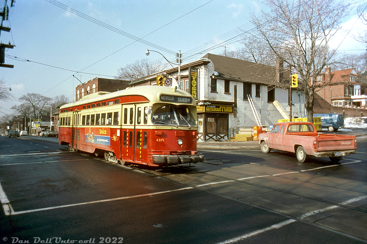 TTC PCC 4371 rattles through the intersection of Queen Street and Beech Avenue, heading eastbound through "The Beaches" neighbourhood on the Queen route for nearby Neville Loop. 

The Chalet Steakhouse, Restaurant & Tavern in the background appears to be undergoing renovations. The building remains today, home to a local watering hole.

Original photographer unknown, Dan Dell'Unto collection slide.