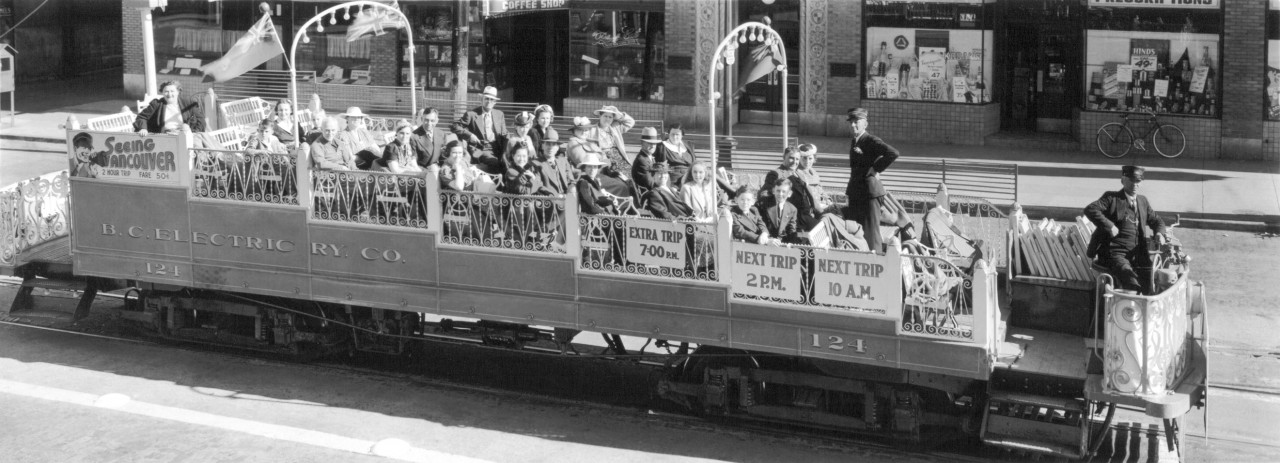 BC Electric Railway Co Observation Car 124, Teddy Lyons Conductor.  Andy and Joe Morin are seated above Next Trip 2PM sign.  The Black Cat Cafe at 1486 W Broadway, just east of Granville st. is in background.  Train is heading west.