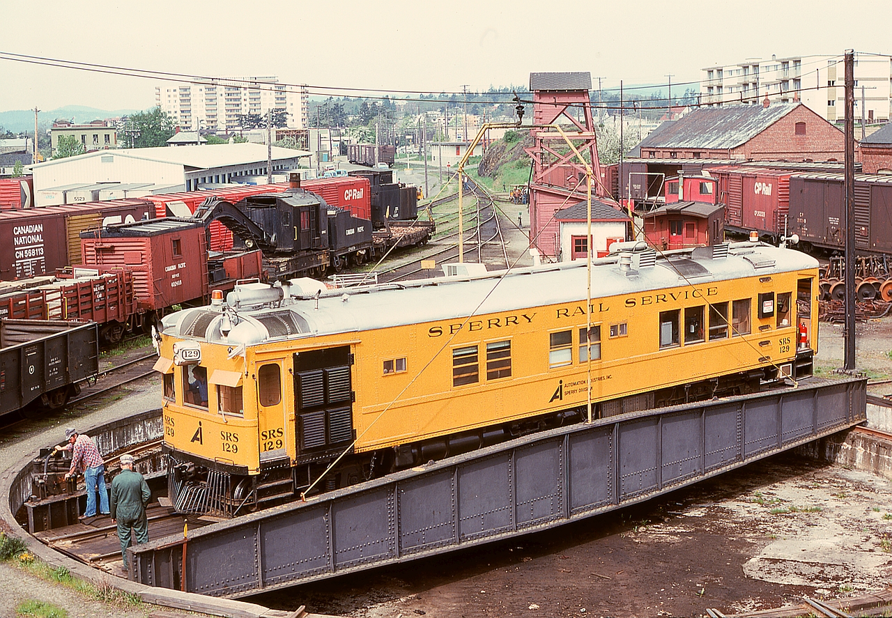 On the CP E&N turntable at Victoria on Saturday 1976-05-01, Sperry car SRS 129 (which dates from 1925 as Lehigh Valley 29) is rotated in a time warp of similar-age CP facilities and equipment, most notably the 1920s Industrial Works 100-ton auxiliary crane 414326.

In the distance above the centre of the car is the simple 1972 concrete block depot at mileage 0.8 which replaced the downtown depot at mileage 0.0 at Store Street.
