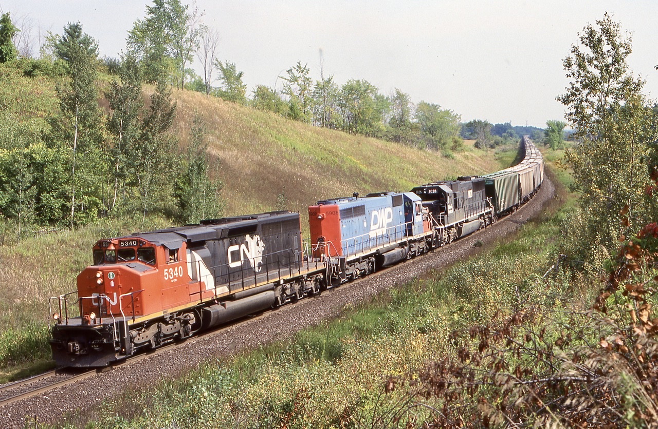 This by far was one of my favourite early on railfan spots. A number of us used to meet up at mile 30 typically on Sunday just to take in some action. The hike up the hill where the golf course now is was always worth while with nice scenic shots in either direction. One could easily spend an afternoon here and we often did. Unfortunately with the Pro Links golf course on either side of the tracks today along with a bridge to the east of this shot, it is not quite the same here anymore not to mention how much greener has filled in the location eliminating this angle completely. I’m glad I spent the time I did here. This train was an interesting one as it was a rare unit grain train that started out with another IC SD70 in the lead. Unfortunately it was replaced by 5340 in Sarnia. This still made for a nice mix of power and it was always nice catching the DWP units in any consist. I never photographed from the hill on the other side as the lighting never worked but looks like it would have made a nice shot on an overcast day.