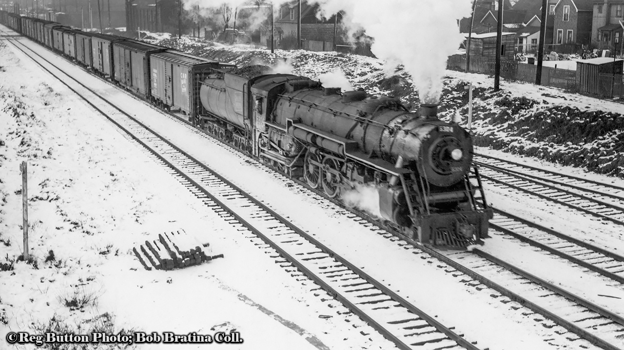 CNR U-3-a 6304 leads an eastbound freight out of Hamilton about to duck under the Emerald Street footbridge.  In the background above the second boxcar, the former Cataract Power Company building can be seen on Victoria Avenue North.  Founded in 1896, the building (built in sections from 1896 – 1907) originally housed a steam boiler, later becoming a hydro substation in 1898 from the Decew Falls Generating Station near St. Catharines.  It would become part of the publicly owned Hamilton Hydro in 1930.  The building has continued to house a number of businesses in recent years, including Hobo Hardware, and Krown Rust Control.  As of August 2020, the building is on it’s way to becoming Evil Empire Studios, a film studio for various artistic works and production companies.Originally built by ALCO for the Grand Trunk Western in 1927, 6304, and all twelve U-3-a Northerns  (6300 – 6311) would be transferred to the CNR circa 1941-1942.  It would be scrapped in May 1961.More from the Emerald Street footbridge:May 1967 by Doug PageApril 1997 by Arnold MooneyApril 2019 by Jamie Knott