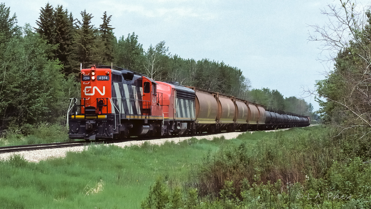 Some history leading up to this photo. On Wednesday the 29th at 10:40, 836 came limping into Redwater with the 4606 and 4294 and took the siding. After stopping, the reason why 836 was struggling became apparent, the 4294 was dead. If you can imagine, within a few minutes, the 4606 is burping and stops, out of fuel also. You can hear the conversation on the section radio. Diesel fuel is ordered and put in. Meanwhile, a unit train of sulphur empties go by heading north at 11:10 with 9159, 9194 and 9164. Next at 11:40, 584 heads out with 1082, 1075 and 1081. Those pair make a nice fill in while the units are being refueled :^). Finally at 13:10 they start them up, but, only the 4606 will run. At 13:20, decided to go home. A half hour later they are back, still having problems. At 15:00 they left and made it to Edmonton. At 19:00 a new 836 and crew come rolling through town. They now have the 4314 and 9108 for power. This photo shows the 4314 returning on Thursday at 15:25 as the extra approach's Kerensky siding.