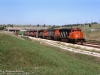 Six high-horsepower road units put their combined 18,600 horsepower to work pulling a rerouted CN #431 out of the <a href=http://www.railpictures.ca/?attachment_id=41004><b>Townline Tunnel</b></a> on the climb out from underneath the Welland Canal. CN SD40-2W 5356, M636 2315, GP40's 9306, 9307, 9308 and GP40-2L(W) 9402 are typical of the mid-80's CN mainline power of the era, of which the widecab units faired best in terms of longevity.
<br><br>
The train is coming out of the tunnel on CN's Cayuga Sub near Brookfield, the other two tracks being CR's former Canada Division (CASO) line (sold to CN & CP two years earlier) and a middle shared track. The line through here, once a part of the busy New York Central corridor through Southern Ontario, today is a shadow of its former self in terms of trains and trackage.
<br><br>
<i>Reg Button photo, Dan Dell'Unto collection slide.</i>