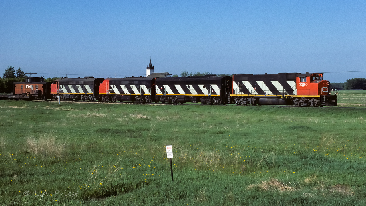How to make a GP38 look good, add 3 f units. :^)  A cabhop at the northend of Egremont siding, on the way north to pickup a loaded unit train of sulphur. Cab 79282 at the rear, time was 8:30.