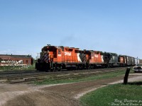 An all-GMD/EMD consist rolls through Guelph Junction on a sunny July afternoon: Extra 5003 West, with CP GP35's 5003, 5020, leased <a href=http://www.railpictures.ca/?attachment_id=32121><b>N&W SD40-2 1651</b></a>, and little SW1200RS 8124 trailing. The edge of the <a href=http://www.railpictures.ca/?attachment_id=39147><b>station</b></a> is visible to the left, with replacement crossing gates stationed nearby. An old CP heavyweight passenger car demoted to OCS/work service sits on a track behind. Any hints as to whose car is parked on the right?
<br><br>
<i>Reg Button photo, Dan Dell'Unto collection slide.</i>