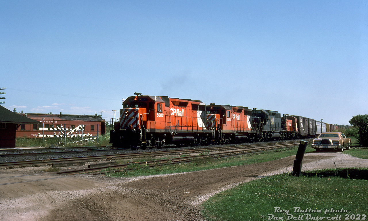 An all-GMD/EMD consist rolls through Guelph Junction on a sunny July afternoon: Extra 5003 West, with CP GP35's 5003, 5020, leased N&W SD40-2 1651, and little SW1200RS 8124 trailing. The edge of the station is visible to the left, with replacement crossing gates stationed nearby. An old CP heavyweight passenger car demoted to OCS/work service sits on a track behind. Any hints as to whose car is parked on the right?

Reg Button photo, Dan Dell'Unto collection slide.