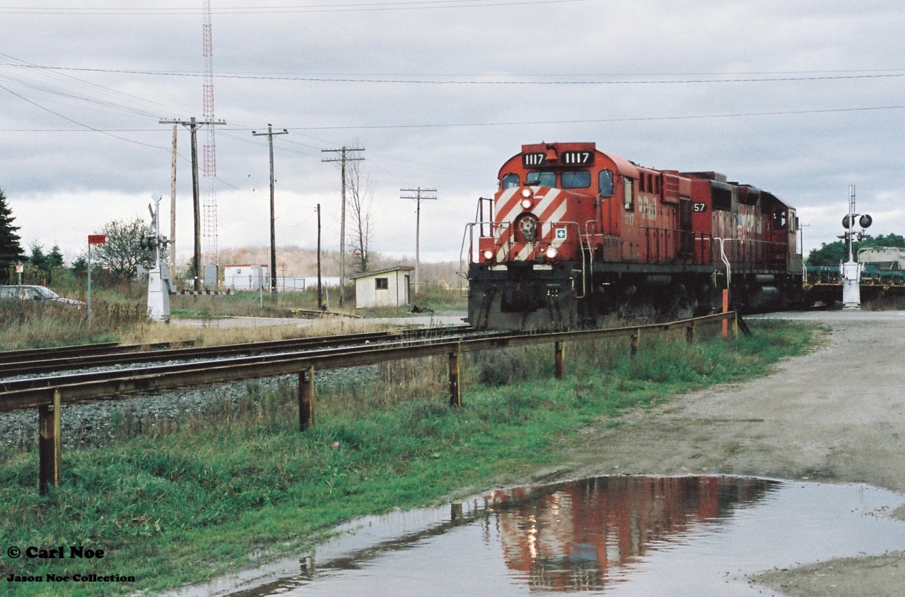 A brief reflection helps to brighten-up an otherwise overcast fall day as CP 141 heads westbound with Control Cab 1117 and GP38-2 3057 through Ayr, Ontario on the Galt Subdivision.