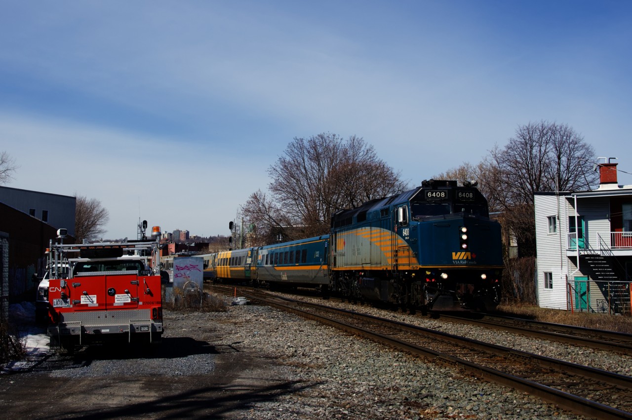 VIA 60 from Toronto is passing a couple of CN trucks at the St-Ambroise crossing.