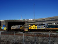 VIA 63 with clean wrap VIA 6445 for power is passing a parked CN B730, whose lead unit is barely peaking out of the Turcot Interchange.