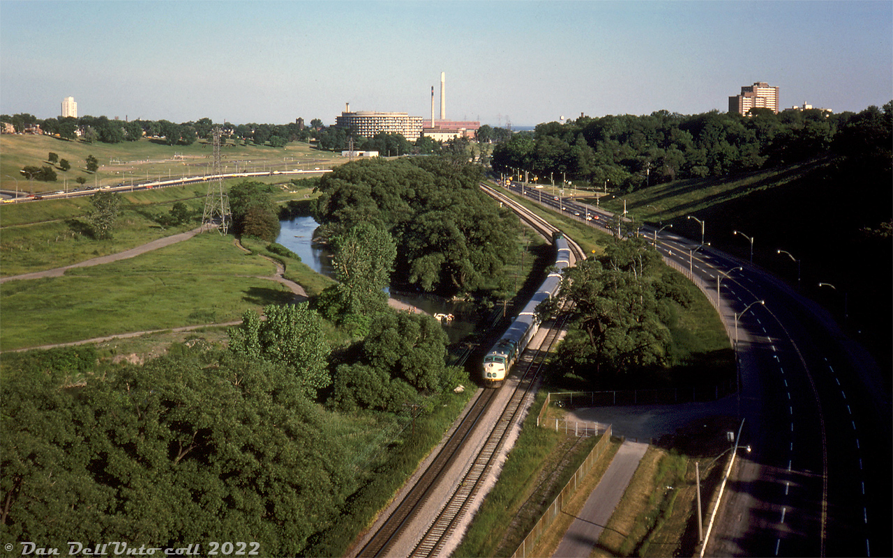 An unknown GO 900-series APCU (former ONR FP7 convered into a HEP cab car) leads a short Richmond Hill line northbound on CN's Bala Sub just south of CN Rosedale, as seen from on top of the Bloor Viaduct one sunny Summer evening in 1979.

The train is heading northbound through Toronto's Don Valley out of the city on CN's Bala Subdivision, running alongside Bayview Avenue on the right. Visible on the left is the namesake Don River, and on the other side the Lower Don Trail, CP's Don Branch (Belleville Sub) and the Don Valley Parkway. Beyond that is Riverdale Park East, and Broadview Avenue at the top of the hill. The rounded building in the distance is the old Riverdale Hospital (now Bridgepoint Hospital, and the old building pictured has been demolished and replaced). The red building behind with the smoke stacks? The famed R.L. Hearn Generation Station in the portlands.

Original photographer unknown, Dan Dell'Unto collection slide.
