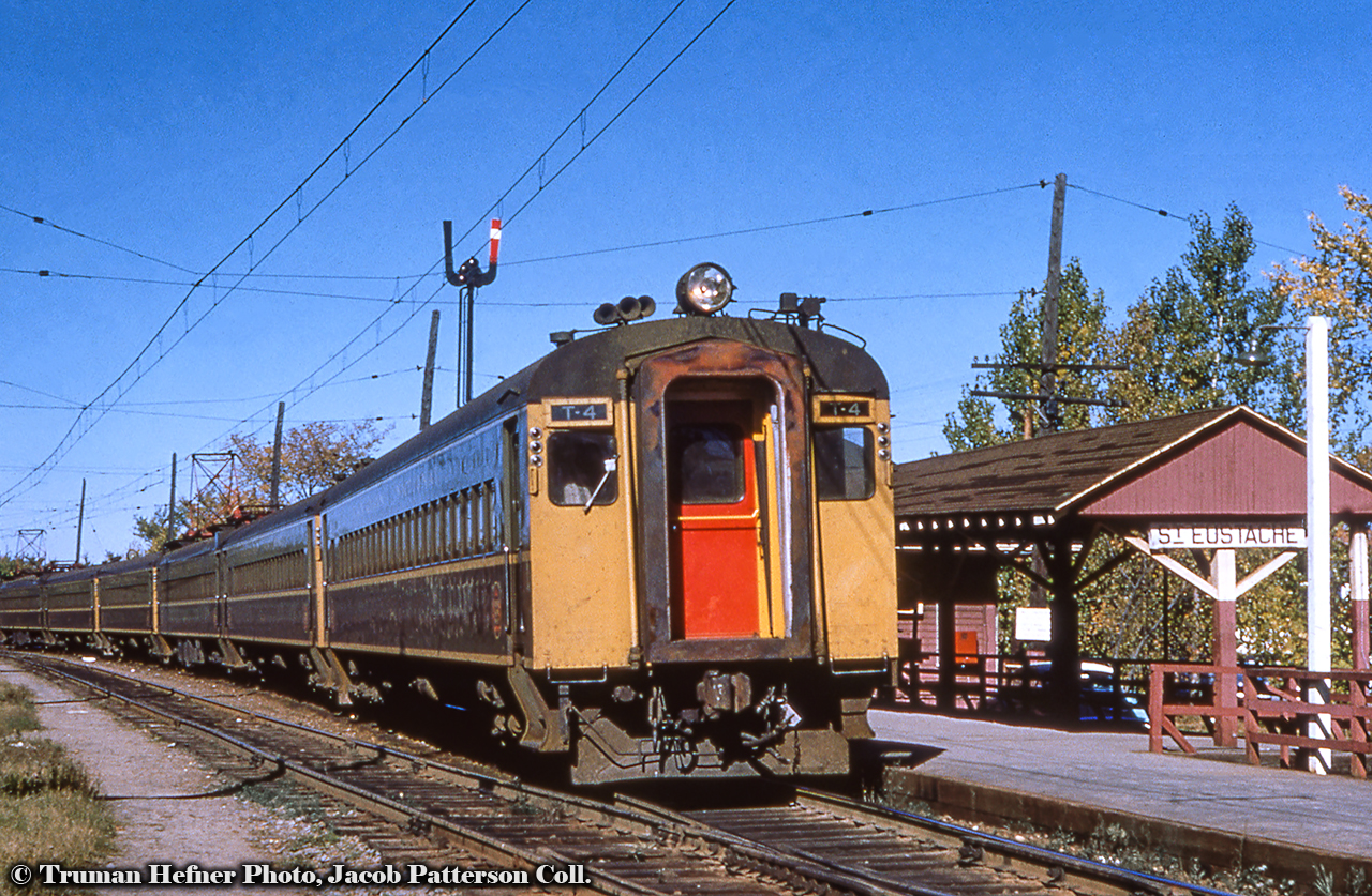 A follow up to an earlier posting on these electric operations.Canadian National Railway EMU Trailer T4 is now in the lead position waiting to depart Saint Eustache for Gare Centrale in downtown Montreal with a mid-afternoon commuter on a sunny fall day.  Date is approximate, as cars were delivered in 1952 and have a few years worth of wear and tear on them.  Saint Eustache station (formerly Saint Eustache sur le Lac per a 1945 postcard) would be renamed Deux Montagnes station in 1963, placing this shot about 1960 give or take a few years.  This appears to be a mid-afternoon train, and based on the October 1960 CNR timetable, could put it as train 362, departing Saint Eustache at 1330h, or train 364, departing at 1430h.  T4 would later become 6743 during the 1969 repainting and renumbering.In an effort to modernize it’s ageing fleet of wooden commuter cars, CNR ordered eighteen Electric Multiple Unit cars in 1952 from Canadian Car & Foundry, six of these being motors numbered M1 – M6, and the other twelve being trailers, numbered T1 – T12.  These would enter service in September 1952, with the motor always leading outbound from Gare Centrale.  Further information can be found in this September – October 1952 publication by the CRHA.  The EMU sets would be repainted to CN’s black and grey scheme in 1969 and would be renumbered to the 6700 series along with all other Montreal electric motive power.  The six motors would become 6730 – 6735, and the trailers 6739 – 6749.  Of the eighteen cars, four would not survive to the end of service in 1995.  Motors 6731, 6732 would be destroyed by fires in 1994 and circa 1980 respectively, while trailer 6748 would be scrapped due to corrosion in 1993, and trailer T8 was destroyed in a fatal head on collision in 1960.The CN electric era drew to a close on June 2, 1995 with AMT taking over by the end of the year.  Now under the name EXO, the line has been shut down in recent years and all infrastructure removed for rebuilding into the grade separated, driverless REM light rail system.  More on this from Michael Berry here (1), and here (2), plus an article from Railfan & Railroad here.The remaining fourteen cars survive in preservation throughout North America:Motors 6730, 6733, 6735 and trailer 6746 at the South Carolina Railroad Museum in Winnsboro.Motor 6734 and trailer 6742 at Exporail.Trailers 6739, 6743, 6745, 6749 to the Conway Scenic Railroad in North Conway, New Hampshire.Trailer 6740 to the Alberta Railway Museum in Edmonton.Trailers 6741, 6744, 6747 to Alberta Prairie Railway Excursions in Stettler.More EMU:6731 at Portal Heights, June 1979 by Peter Jobe6733 at Val Royal, June 1991 by Glenn Courtney6734 on display at Exporail, April 2018 by Michael Berry6743 arriving at Mont Royal, July 1977 by John EullTruman Hefner Photo, Jacob Patterson Collection Slide.