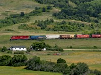 Westbound grain empties pass a farmyard in the Assiniboine River bottomlands on CP's North main. On both sides of the Assiniboine lies 1.8% grades both ways. Also 1.5 % grades each way between Birtle and Solsgith and 2% each way out of the terminal of Minnedosa gave this line the name "Manitoba's mountain railway.