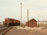 At Prince Albert in 1976, clear evidence of steam days remained as the foundation for the water tower stood firmly in the CP yard, with a trio of RS-23s, 8015+8017+8018, passing by on Wednesday 1976-09-29, preparing to take a train to Meadow Lake.