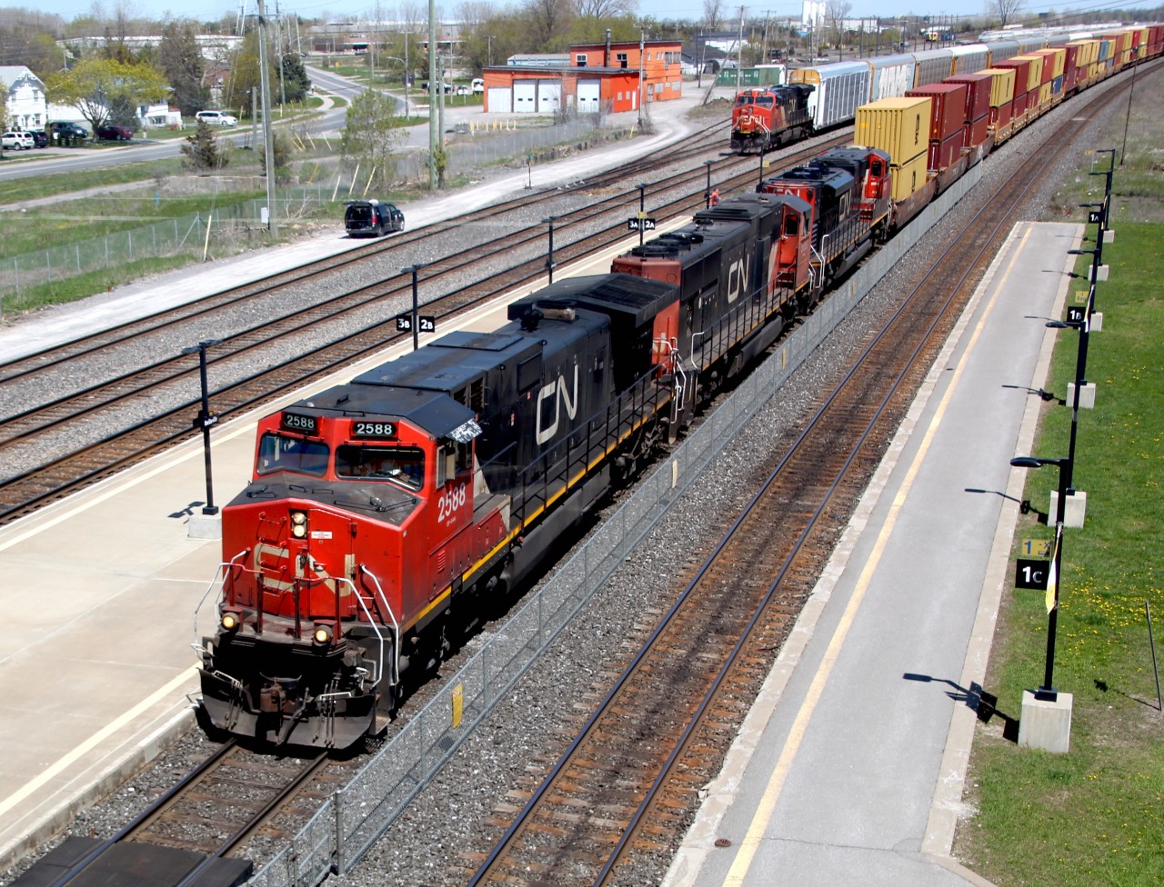 A perfect Sunday in May afternoon finds a power mix of CN 2588 (C44-9W), CN 5653 (EMD SD75I) and CN 8815 (EMD SD70M-2) leading an extremely long intermodal. This mix is resuming its journey westward after a short crew change at Belleville ON.  Photo was taken from the walkover at the Belleville, VIA Station looking eastbound over the yard.  In the background an idle CN 2989 (GE ES44AC) waits with a string of auto racks.