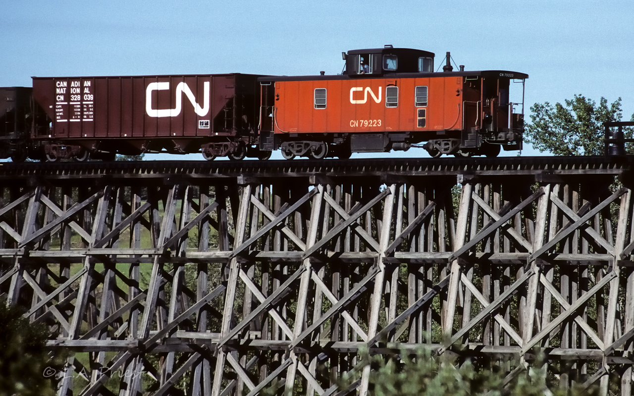 A unit train is passing over the wood trestle at mile 17.7 as it returns to Edmonton at 8:30. The chimney with the top missing, to the right of the cupola, sure looks odd.
