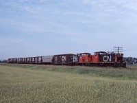 GMD-1s 1008 and 1050 lead an eastbound away from Portage la Prairie and towards Winnipeg's Symington Yard. By this time, branch lines requiring light weight power were becoming fewer and fewer as the Prairie Branch Line Rehabilitation Program (implementing the recommendations of the 1977 Hall Commission on Grain Handling and Transportation for branch line rationalization) was well under way. In a few days, on August 1st, the Western Grain Transportation Act will take effect, effectively abolishing "the Crow" rate and ramping up changes to the handling of Canadian grain. At the time of the photo, CN had already converted 12 GMD-1s to B-B trucks and would eventually convert 46 of 83 A1a-A1A units (including the 1050 and former NAR GMD-1s) to that configuration. Lead unit 1008 would be re-manufactured as the 1602 in 1988 and re-trucked to B-B unit 1432 in 1999.