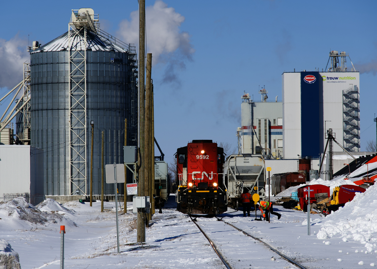 A crewmember is throwing a switch as CN 519 prepares to depart the St-Jude Spur after bringing cars here for the third time this day. CN brings cars to Transbordement St-Hyacinthe, which switches cars for a number of clients located here.