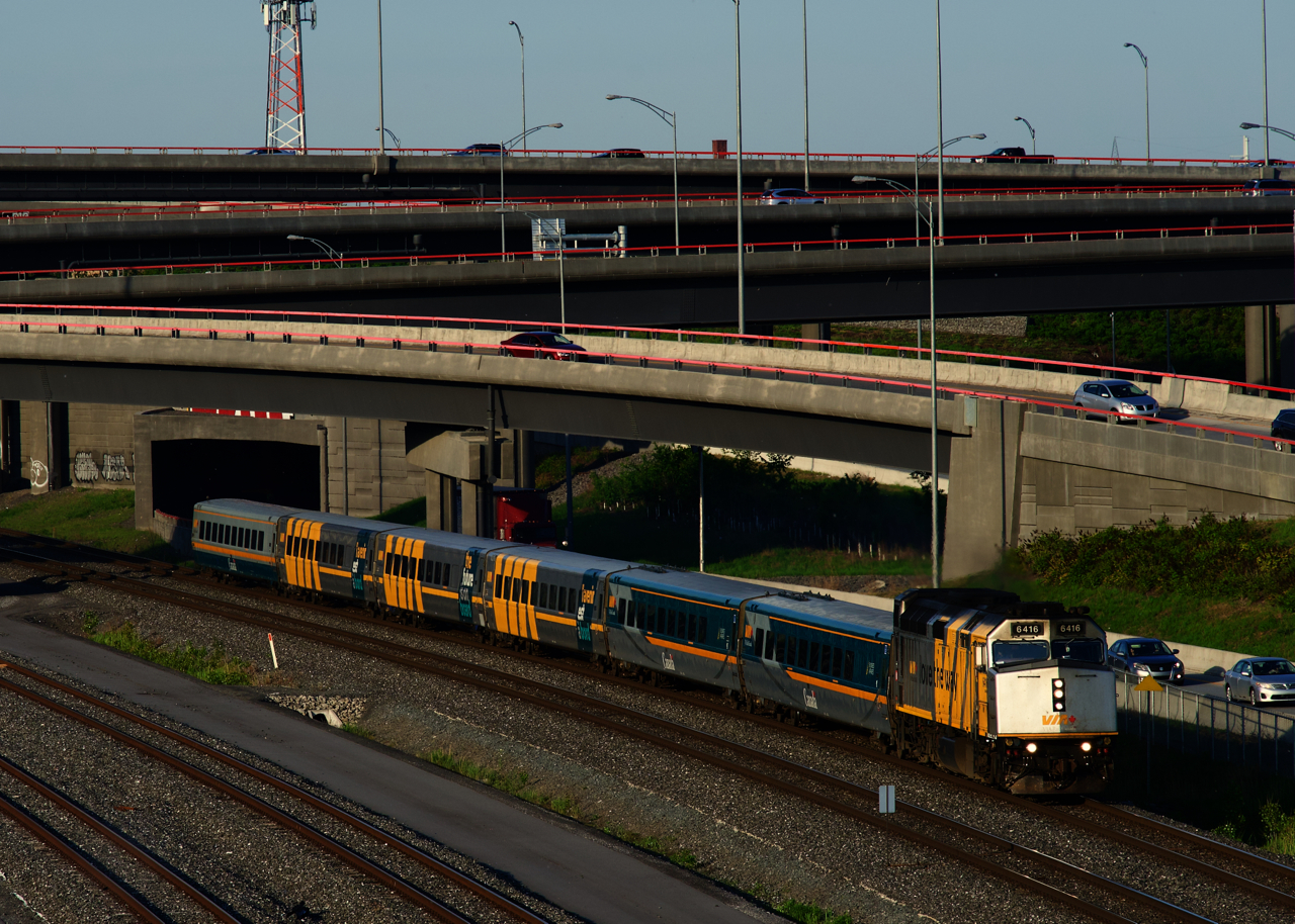 The last train of the day for Toronto is passing the Turcot Interchange with wrapped VIA 6416 and six LRC cars.
