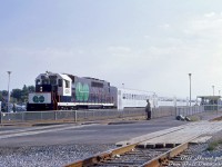 During the early months of the Ontario Government's experminental GO Transit commuter operation, GP40TC 606 heads up an eastbound commuter train bound for Pickering, seen departing Scarborough GO Station and about to cross the St. Clair Avenue East grade crossing. Commuters and auto traffic patiently wait for the train to clear the multiple-track mainline crossing on CN's busy Kingston Subdivision (a <a href=http://www.railpictures.ca/?attachment_id=46314><b>grade separation</b></a> here would follow a decade later).<br><br>What we know today as the sprawling GTHA train and bus commuter operator GO Transit was initially launched as a single line (the Lakeshore line, from Oakville to Pickering), run by eight specially-built GMD GP40TC commuter locomotives, an order of 40 single-level commuter cars built by Hawker Siddeley Canada, and nine self-propelled versions intended to handle lighter runs and off-peak service. All of this was envisioned as a forward-thinking trial service by the government of the day to help curb the effects of congestion due to current and future projections of growing automobile traffic coming in and out of downtown Toronto. Its success, coupled with growing suburban sprawl popping up around Toronto, would result in the beginning of a new bus network three years later, and launches of multiple new commuter lines and expansions over the decades that followed.<br><br><i>J. William (Bill) Hood photo, Dan Dell'Unto collection slide.</i>