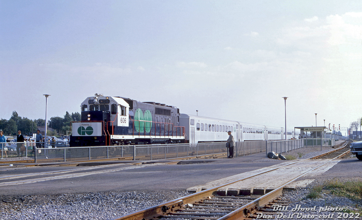 During the early months of the Ontario Government's experminental GO Transit commuter operation, GP40TC 606 heads up an eastbound commuter train bound for Pickering, seen departing Scarborough GO Station and about to cross the St. Clair Avenue East grade crossing. Commuters and auto traffic patiently wait for the train to clear the multiple-track mainline crossing on CN's busy Kingston Subdivision (a grade separation here would follow a decade later).

What we know today as the sprawling GTHA train and bus commuter operator GO Transit was initially launched as a single line (the Lakeshore line, from Oakville to Pickering), run by eight specially-built GMD GP40TC commuter locomotives, an order of 40 single-level commuter cars built by Hawker Siddeley Canada, and nine self-propelled versions intended to handle lighter runs and off-peak service. All of this was envisioned as a forward-thinking trial service by the government of the day to help curb the effects of congestion due to current and future projections of growing automobile traffic coming in and out of downtown Toronto. Its success, coupled with growing suburban sprawl popping up around Toronto, would result in the beginning of a new bus network three years later, and launches of new commuter lines and expansions in over the decades that followed.

J. william (Bill) Hood photo, Dan Dell'Unto collection slide.