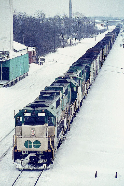 Dug up another photo from the old days of GO power pulling freight. I last posted a shot of this train around 9 years ago (#8920) so I guess another is valid. MAC-bound (CN) GO 8901, 9804, 710 and 709 waiting out a signal at Aldershot due to passenger train congestion ahead.  The freight would eventually run up the Halton.
CP leased GO power on weekends back then, and CN, to a lesser extent, did as well. This was a late day image, and I was glad to at least get this much of a shot before the light failed.
GO 9801 and 9804 renumbered 501 and 504 in 1975. In 1991, 710 and 709 went to CN; numbered 9677 and 9676.
Thats Lemonville Rd bridge in the background. The chimney is part of the long gone Burlington Brick Plant.