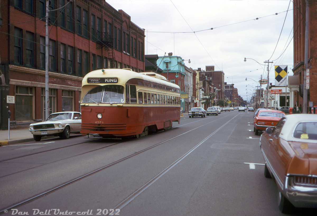 Streetcars, land yachts and pony cars: TTC PCC 4574 (an ex-Cincinnati A9-class built by St. Louis Car in 1947) operates on the King route as it nears the downtown core of Toronto, heading eastbound in traffic along King Street at Duncan Street. Street parking in downtown Toronto was still "in" back in the 70's, even on a main thoroughfare such as King Street. And why not? Everyone needed a place to park their big Detroit land yacht, Mustang or VW beetle.Today, this part of King Street has been turned into a transit priority corridor (two curb lanes removed along King between Bathurst and Jarvis, and no automobile through-traffic) in an effort to improve transit performance and encourage urban friendly usage. That row of Victorian-era storefronts at the southwest corner of King & John in the background (note green roof) miraculously still stands in 2022, amid a swarm of modern hi-rises and office towers.Original photographer unknown, Dan Dell'Unto collection slide.