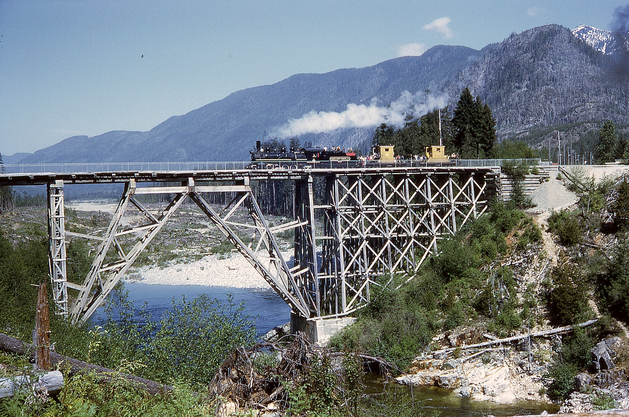 Precisely fifty-one years ago today, on Saturday June 5th 1971, Canadian Forest Products operated their ALCo 2-8-2 locomotive 113 on passenger excursions on Vancouver Island in the Nimpkish Valley from Woss Camp to Woss Lake and return, in conjunction with a Loggers’ Sports Day.  Just west of operating headquarters at Woss Camp, a combination rail-and-road bridge crossed the Nimpkish River, seen here with 113 and two caboose cars westbound two miles to Woss Lake.

This was quite early (only 18 years old) in my railway photography journey, and taken with a borrowed Voightlander rangefinder camera.  To this day I remain surprised at how well it came out, my very first good train action photo.