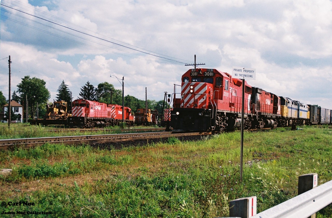 CP 3081 east wastes no time passing Mile 88 on the Galt Subdivision in Woodstock as it heads eastbound to Toronto, with a C424 trailing plus two leased VIA Rail F40PH-2’s during a pleasant summer evening. In the background and assigned to the Woodstock local jobs are C424 4239, GP9u 8239 as well as another GP9u, plus a caboose and the CP Woodstock assigned plow.