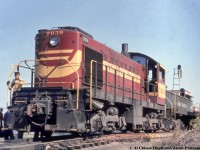 CPR ALCO S2 7039 and hump booster B-100 roll over the hump at St. Luc Yard in 1955, possibly in a demonstration to the crowd off to the left.   7039 wears the short-lived “smiley” paint scheme, debuted on end cab switchers in 1947, and was one of a handful of S2’s modified for multiple unit service with hump boosters B-100, B-101 at St. Luc Yard.  Built by ALCO in 1946, 7039 would be retired in 1984.  B-100, built in 1951 by MLW, would survive much longer, being rebuilt in 1982 to scale test car CPR 420931, and eventually sold for scrap in 2014.  Per a pamphlet given out on a <a href=http://www.trainweb.org/oldtimetrains/photos/cpr_facilities/st_luc_tour.htm>1962 tour of CP’s St. Luc Yard by the National Harbours Board Conference,</a> the St. Luc hump was the first of its kind in Canada, and the first to employ automatic switch control.  Opened in 1950, the hump would be closed in September 1993.<br><br><i>Original Photographer Unknown, Al Chione Duplicate, Jacob Patterson Collection Slide.</i>