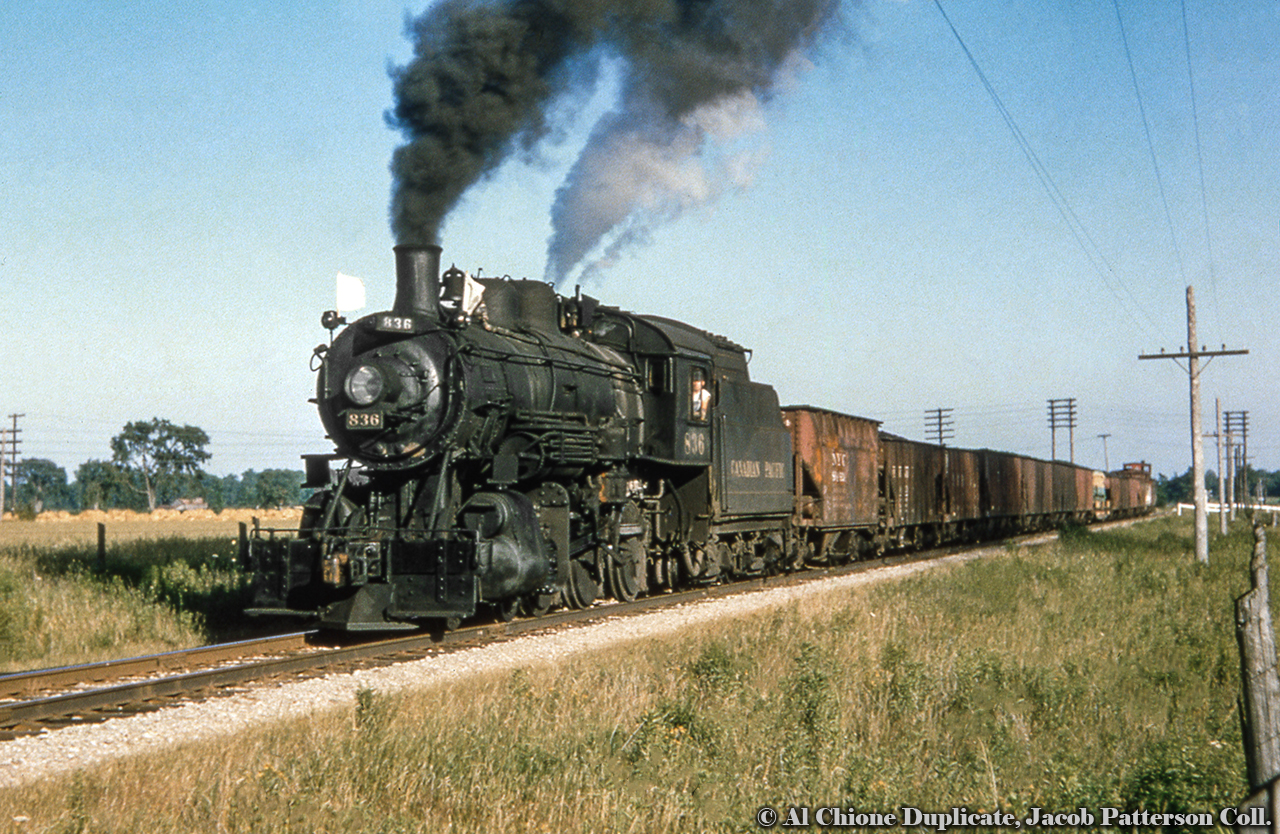 CPR D10f 836 cruises through the countryside at Ostrander with their Woodstock-bound train, predominantly made up of coal loads from Port Burwell off the car ferry “Ashtabula”.Original Photographer Unknown, Al Chione Duplicate, Jacob Patterson Collection Slide.
