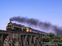 A different take on the bridge at Jordan, CNR 6060 makes it’s return trip from Niagara Falls to Toronto with it’s second last excursion run in Ontario, running under the banner of the “Maple Leaf” in homage to the joint <a href=http://www.railpictures.ca/?attachment_id=49023>Lehigh Valley/Canadian National train</a> discontinued in 1961.<br><br>Two days later, Saturday, July 26 would be 6060’s final run in Ontario with the “Canadian Crusader” special doing a loop around Lake Simcoe, north on the Bala to Washago, and back south via the Newmarket.   A week later, on Saturday, August 2, 6060 would be on train 375 departing Toronto for Edmonton, arriving on Friday, April 8.  It would make the cross-country journey under steam to keep it’s lubricator operational.<br><br>More from this day:<br><a href=http://www.railpictures.ca/?attachment_id=22439>Niagara-bound at Bayview</a><br><a href=http://www.railpictures.ca/?attachment_id=14794>Westbound through Merriton</a><br><a href=http://www.railpictures.ca/?attachment_id=29897>A closeup at Bayview</a><br><a href=http://www.railpictures.ca/?attachment_id=14680>The special arriving back at Toronto</a> <br><br><i>Original Photographer Unknown, Jacob Patterson Collection Slide.</i>