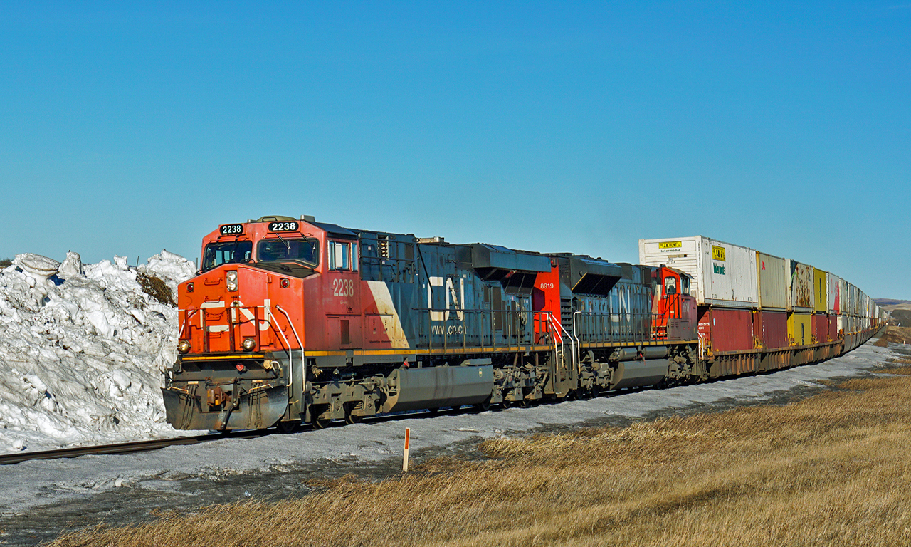 CN 2238 and 8919 pass the remains of a snow drift as they approach Wainwright with a west bound intermodal.