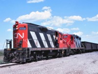 A CN work train unloads ballast along the Craik Subdivision near Chamberlain, Saskatchewan on a very hot afternoon.  A pair of relatively clean GP9s, 4112 and 4237, provide the power for the train.